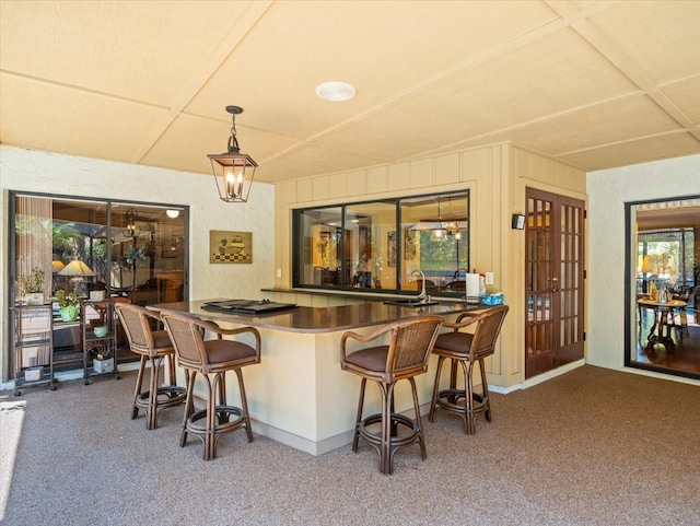 bar featuring a sink, carpet, and decorative light fixtures