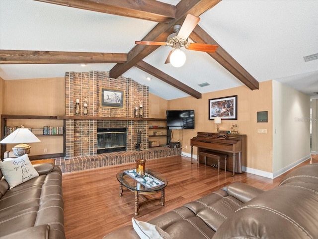 living room featuring wood finished floors, a fireplace, baseboards, vaulted ceiling with beams, and a ceiling fan