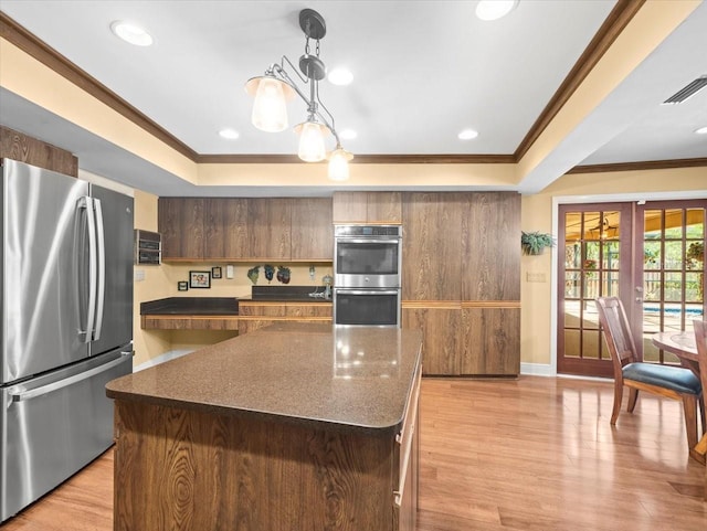 kitchen with crown molding, a tray ceiling, appliances with stainless steel finishes, and visible vents