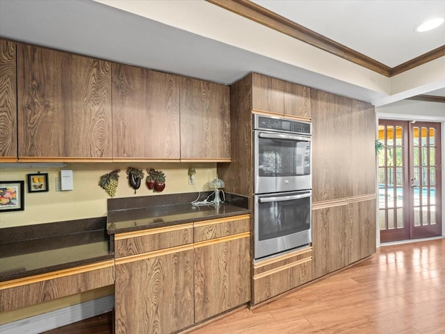 kitchen with crown molding, dark countertops, double oven, recessed lighting, and light wood-type flooring