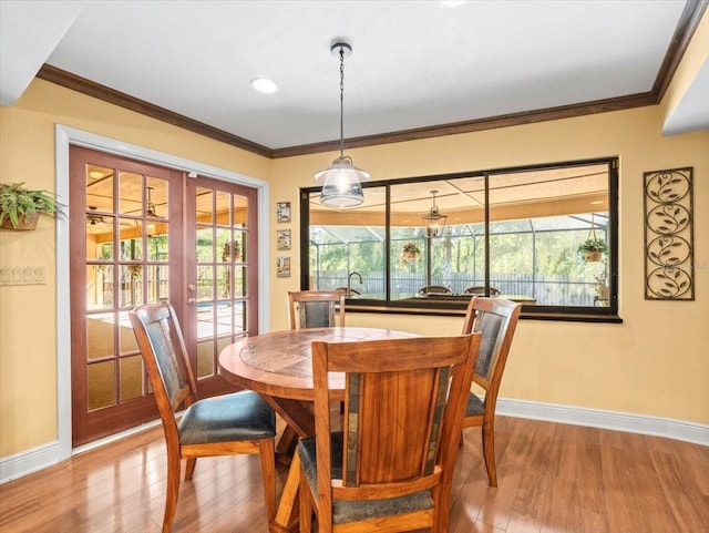 dining space featuring baseboards, ornamental molding, french doors, and wood finished floors