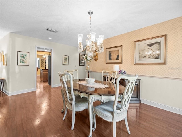 dining space featuring visible vents, an inviting chandelier, wood finished floors, baseboards, and wallpapered walls