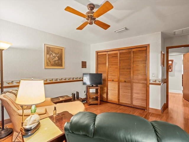 living room with ceiling fan, visible vents, and wood finished floors