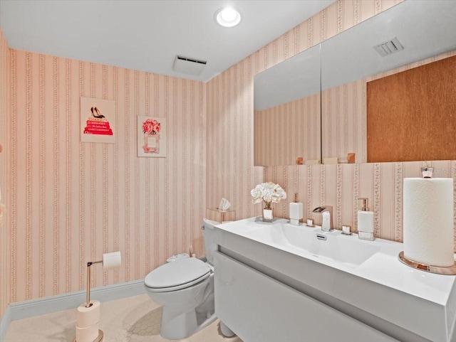 half bath featuring vanity, wallpapered walls, toilet, and visible vents