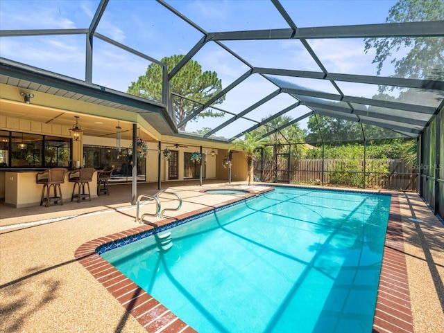 outdoor pool with fence, a patio, outdoor dry bar, a jacuzzi, and a lanai