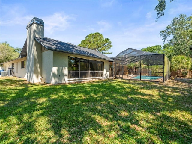 rear view of house with a chimney, a lawn, a fenced in pool, a fenced backyard, and stucco siding