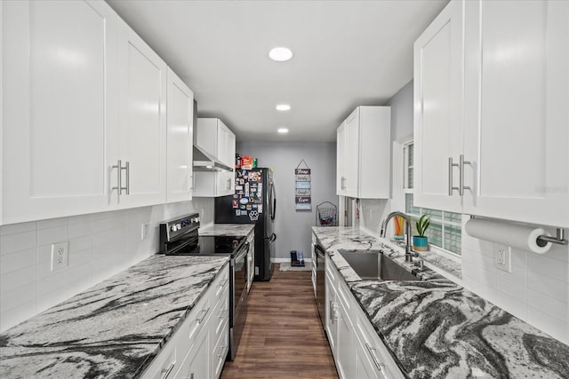 kitchen with wall chimney range hood, stainless steel range with electric cooktop, a sink, and backsplash