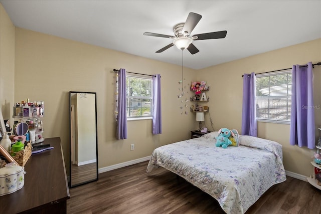 bedroom featuring baseboards, multiple windows, dark wood finished floors, and ceiling fan