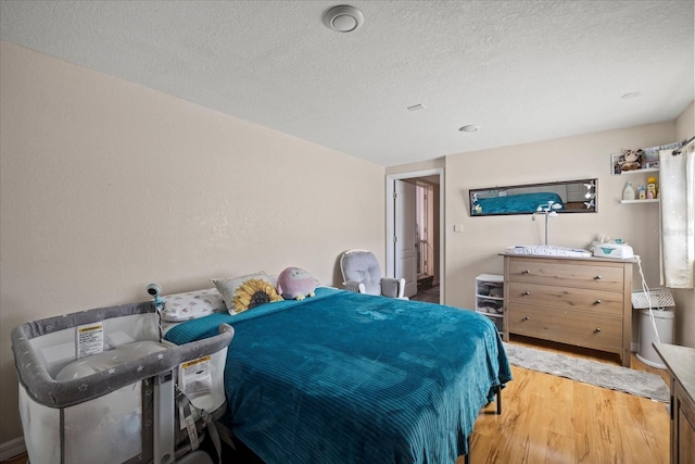 bedroom with a textured ceiling and wood finished floors