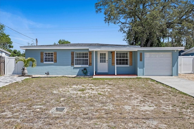 ranch-style house with covered porch, driveway, a garage, fence, and concrete block siding