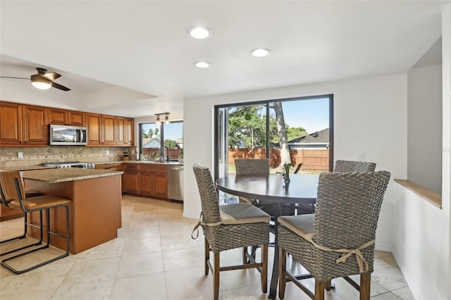 1502 Creekbend Dr, Brandon, FL 33510 - kitchen with brown cabinetry, appliances with stainless steel finishes, tasteful backsplash, a sink, and light tile patterned floors