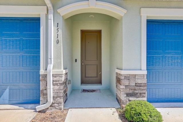 property entrance with stucco siding and stone siding