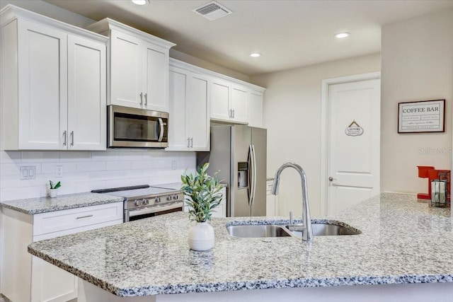kitchen with visible vents, a sink, light stone counters, stainless steel appliances, and white cabinetry