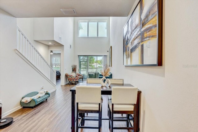 dining space featuring visible vents, baseboards, wood finished floors, and stairway