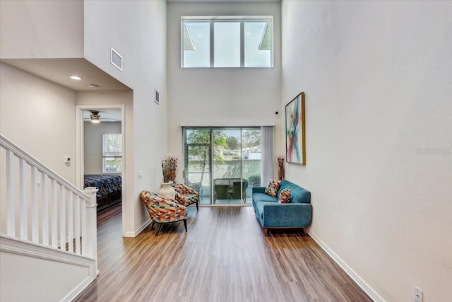 sitting room with baseboards, a high ceiling, wood finished floors, and visible vents
