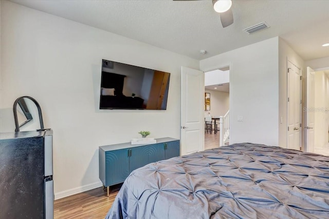 bedroom featuring a ceiling fan, baseboards, visible vents, and wood finished floors
