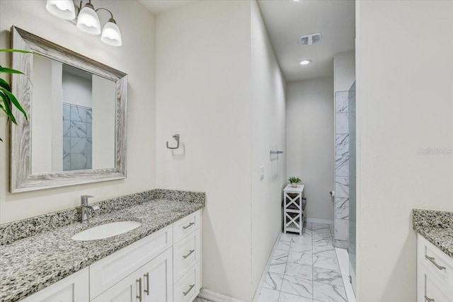 bathroom with a tile shower, vanity, marble finish floor, baseboards, and visible vents