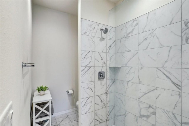 bathroom featuring toilet, baseboards, a tile shower, and marble finish floor
