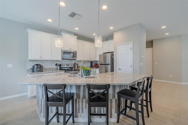 kitchen with appliances with stainless steel finishes, a sink, white cabinetry, decorative backsplash, and visible vents