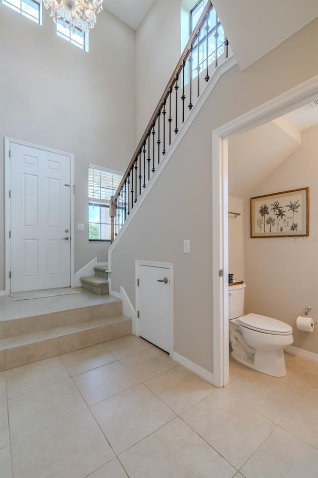foyer entrance featuring a high ceiling, an inviting chandelier, tile patterned floors, and stairway
