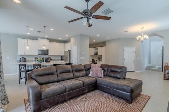 living room featuring visible vents, light tile patterned flooring, baseboards, recessed lighting, and ceiling fan with notable chandelier