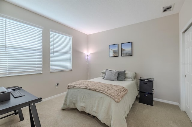 bedroom featuring baseboards, light colored carpet, visible vents, and a closet