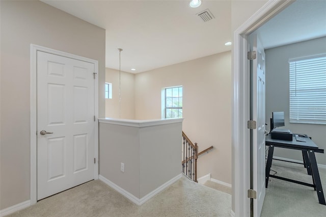 hall featuring baseboards, carpet, and an upstairs landing