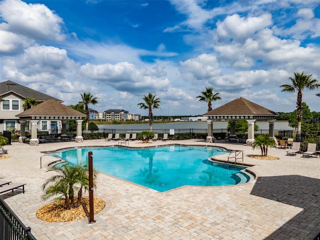 community pool with a gazebo, fence, and a patio area