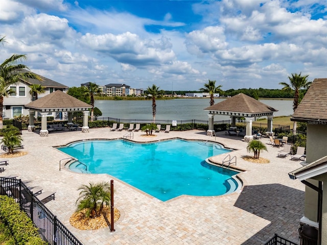pool featuring fence, a water view, a gazebo, and a patio area