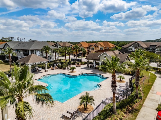 community pool featuring a gazebo, fence, a residential view, and a patio