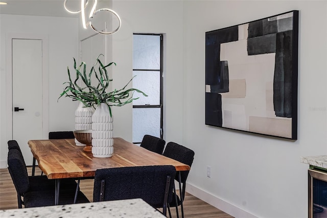 dining area featuring baseboards, a notable chandelier, wood finished floors, and wine cooler