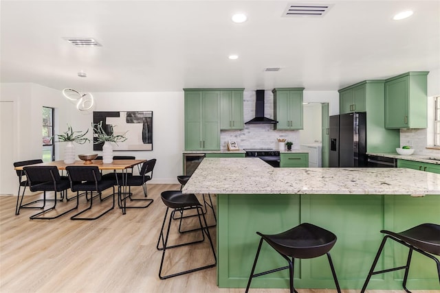 kitchen with range with electric cooktop, visible vents, green cabinets, refrigerator with ice dispenser, and wall chimney exhaust hood
