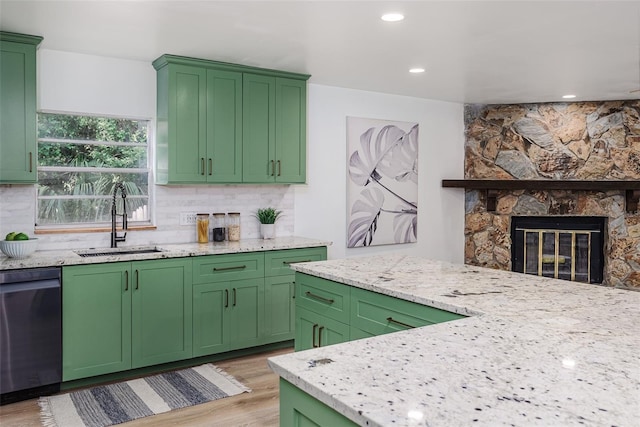 kitchen with stainless steel dishwasher, decorative backsplash, a sink, and light wood-style floors