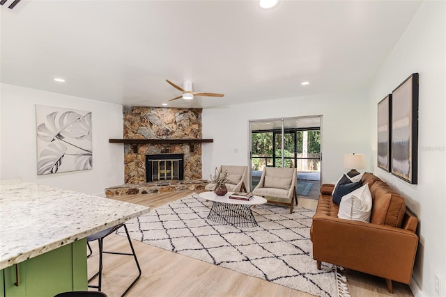living room featuring light wood-style floors, a ceiling fan, recessed lighting, and a fireplace
