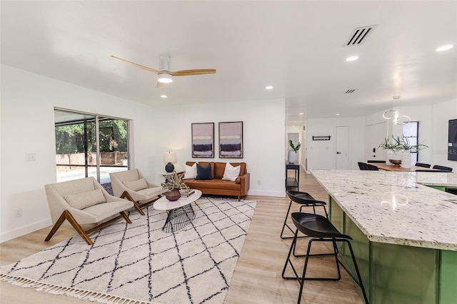 living area featuring light wood-style floors, baseboards, a ceiling fan, and visible vents