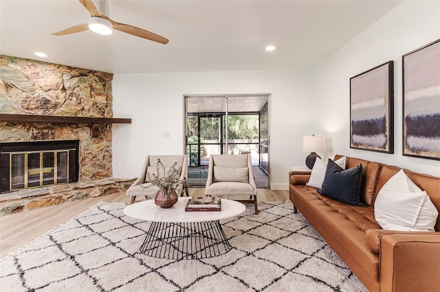 living room featuring ceiling fan, a stone fireplace, recessed lighting, and wood finished floors