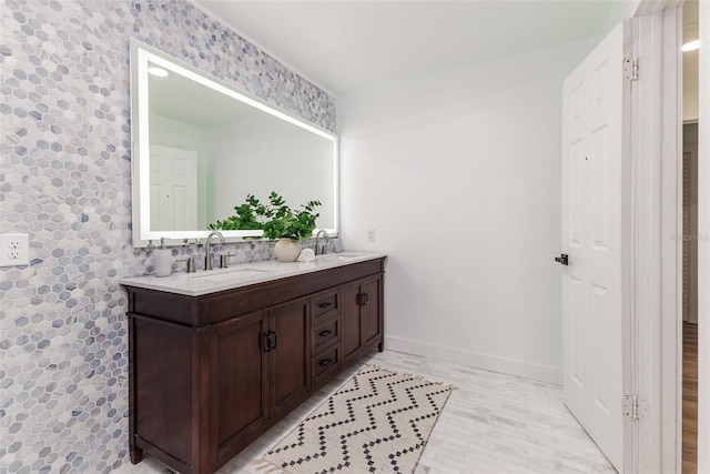 bathroom with baseboards, a sink, and double vanity