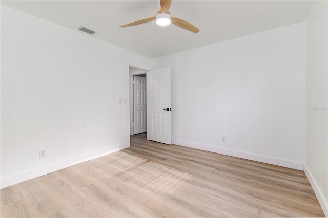 spare room featuring baseboards, ceiling fan, visible vents, and wood finished floors