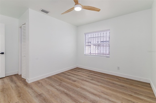 empty room with light wood-style floors, baseboards, ceiling fan, and visible vents