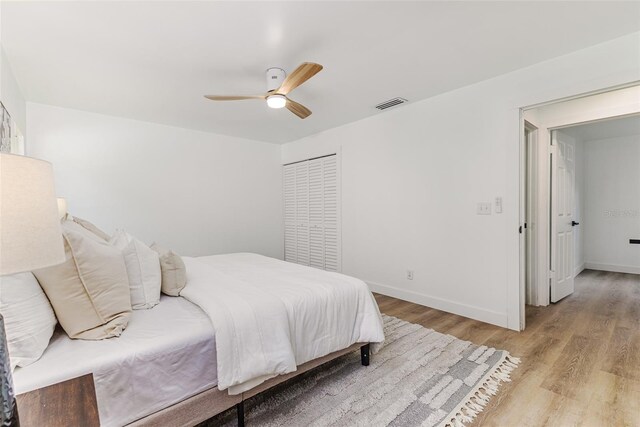 bedroom featuring baseboards, visible vents, ceiling fan, and light wood finished floors