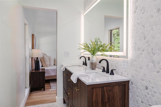 ensuite bathroom featuring a sink, ensuite bathroom, double vanity, and wood finished floors