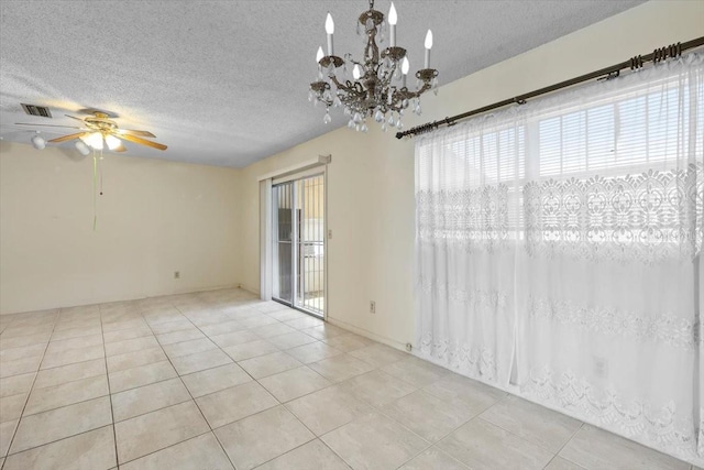 tiled empty room with a textured ceiling, visible vents, and ceiling fan with notable chandelier