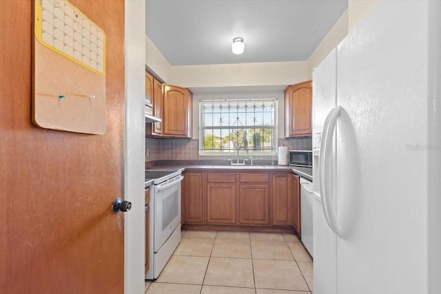 kitchen featuring a sink, dark countertops, backsplash, and white appliances