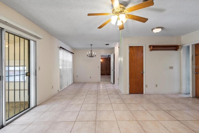 empty room featuring light tile patterned floors, ceiling fan with notable chandelier, and a textured ceiling