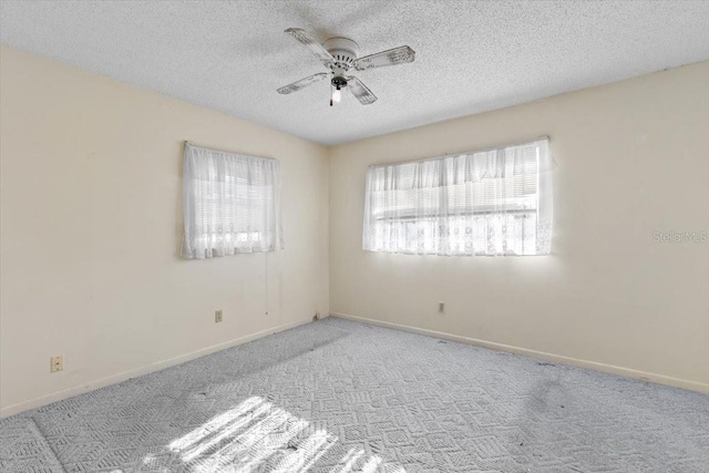 empty room featuring carpet floors, a textured ceiling, ceiling fan, and baseboards