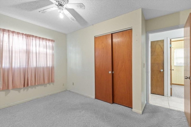 unfurnished bedroom with carpet flooring, a textured ceiling, baseboards, and a closet