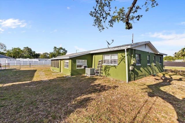 rear view of property featuring a yard, fence, and central AC unit