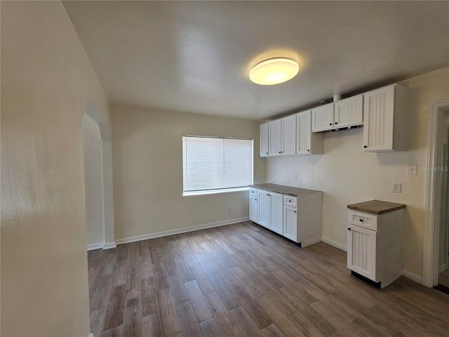 718 Paris Ave S, Saint Petersburg, FL 33701 - kitchen with white cabinets, dark wood-style flooring, baseboards, and dark countertops