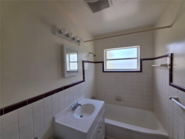 718 Paris Ave S, Saint Petersburg, FL 33701 - full bath with shower / bath combination, visible vents, tile walls, a wainscoted wall, and vanity