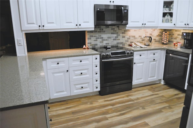 kitchen with light wood-style floors, decorative backsplash, white cabinetry, and appliances with stainless steel finishes